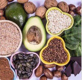 Magnesium BHB inspired keto ingredients including avocado, nuts, seeds, oats, and leafy greens arranged on table.